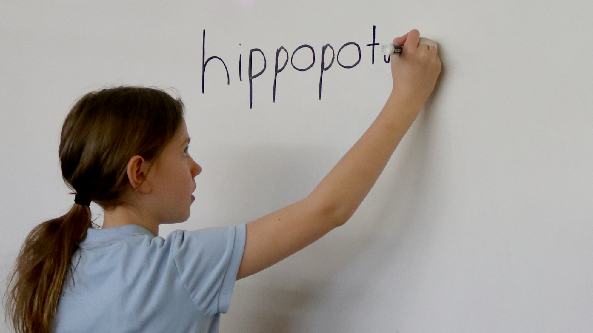 female student writing word on whiteboard
